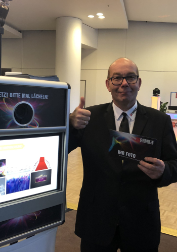 DJ Charlie steht neben der Fotobox mit Daumen hoch