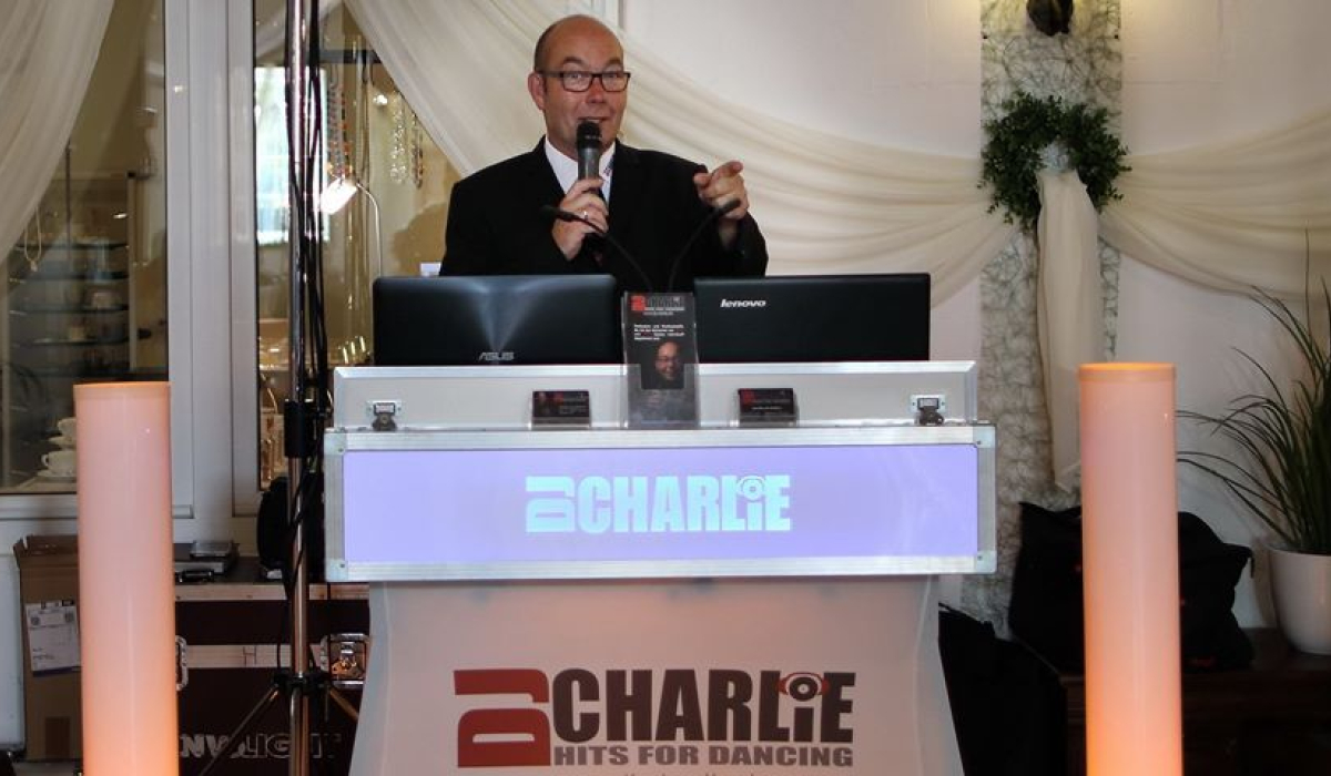 DJ Charlie hinter DJ Pult mit Mikro